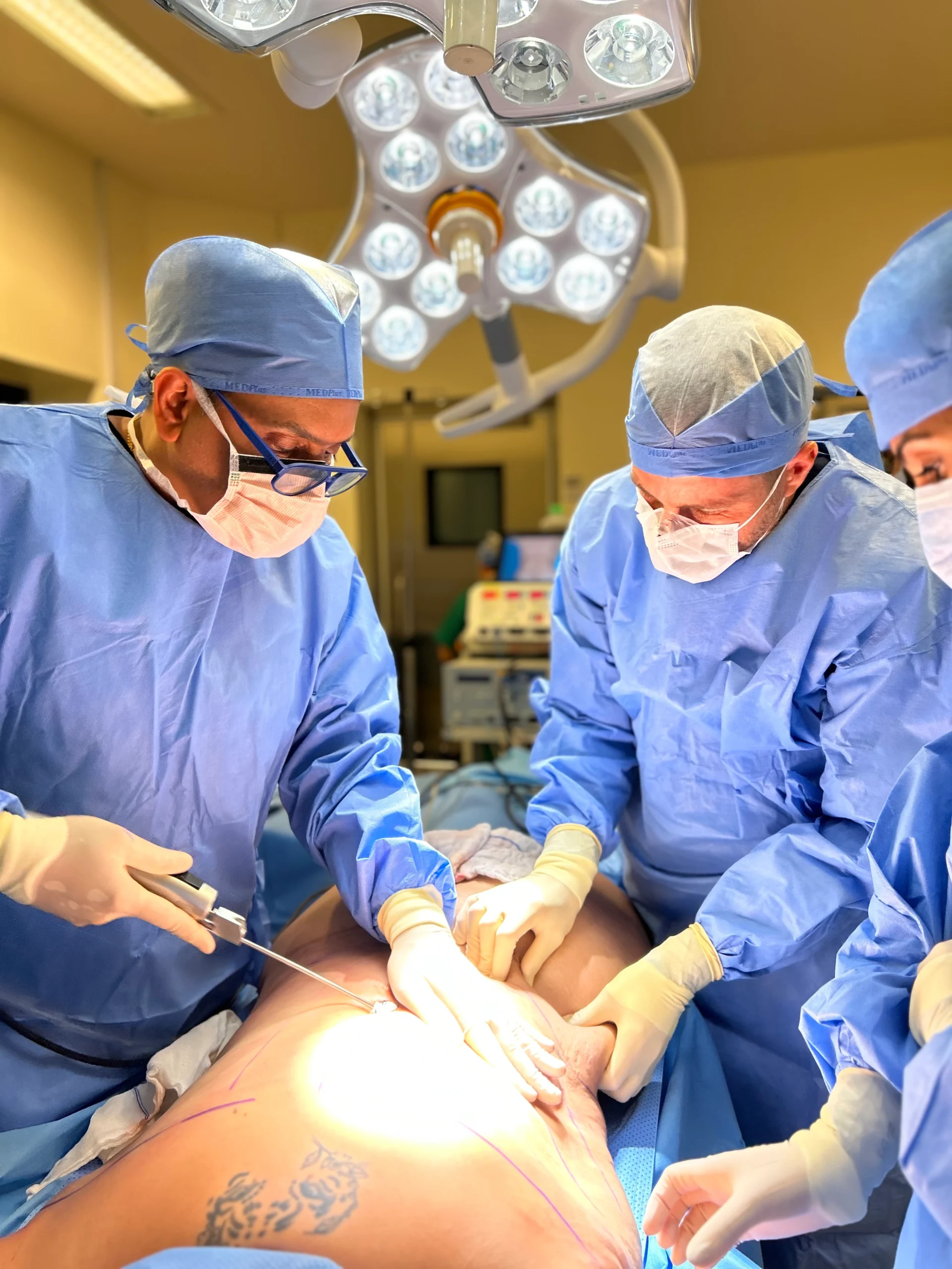 Dr. Sanjay Prakash performing high-definition body contouring and cosmetic surgery in a sterile operating theater.