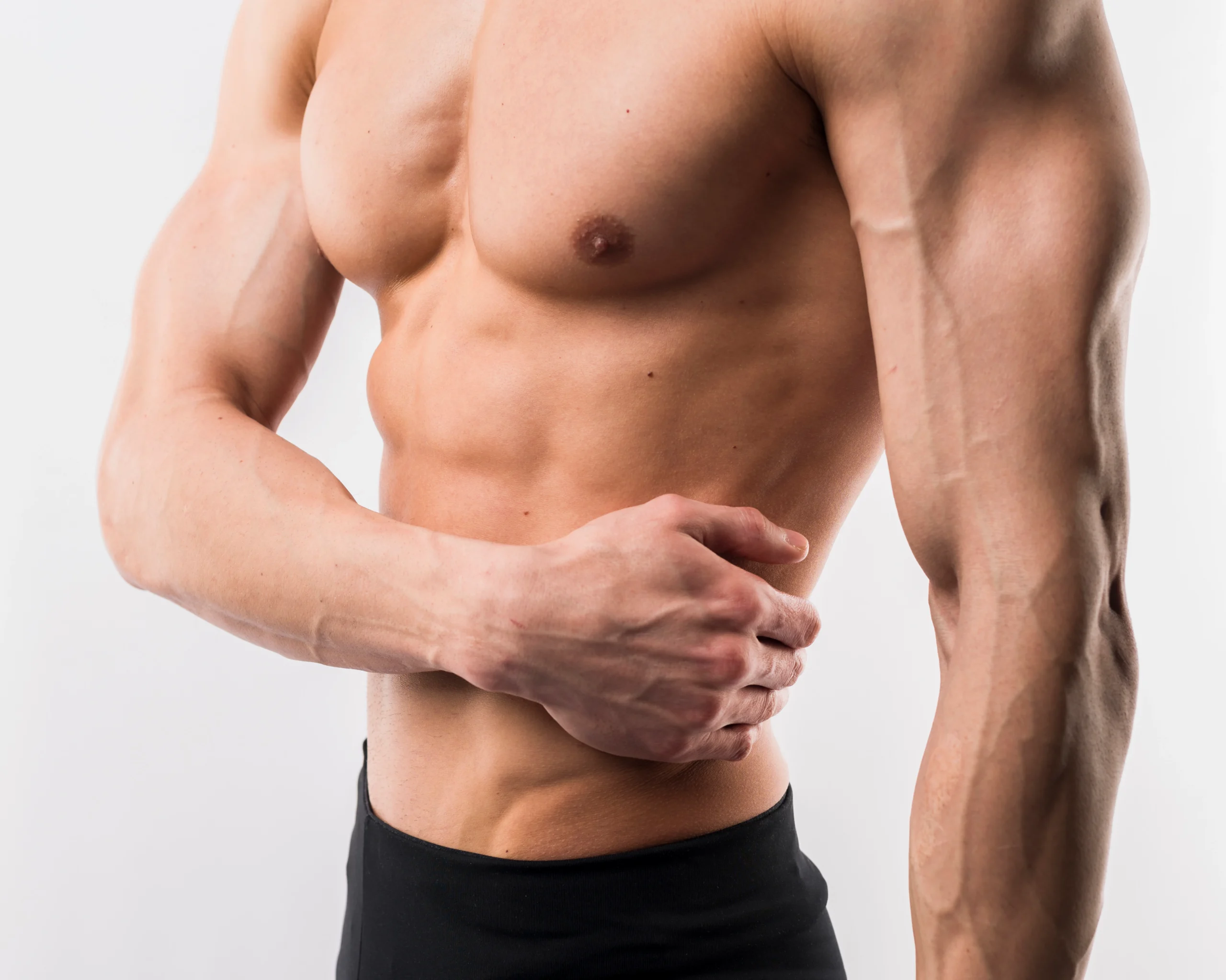 A close-up side-angle view of a fit, shirtless man’s muscular torso and arm, highlighting the clean, contoured borders of his pectoral muscle and abdomen to illustrate clinical benchmarks for selecting the Best Gynecomastia Surgeon UK.